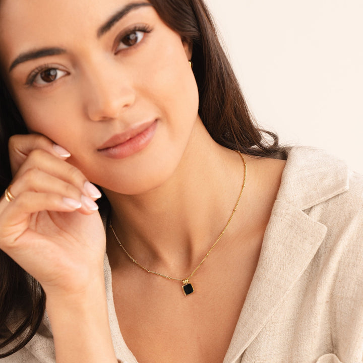 Selina – Collar dorado con piedra oscura.